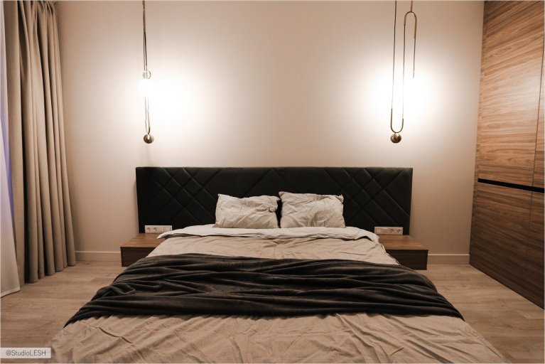 Большая двухспальная кровать в спальне с подвесными светильниками