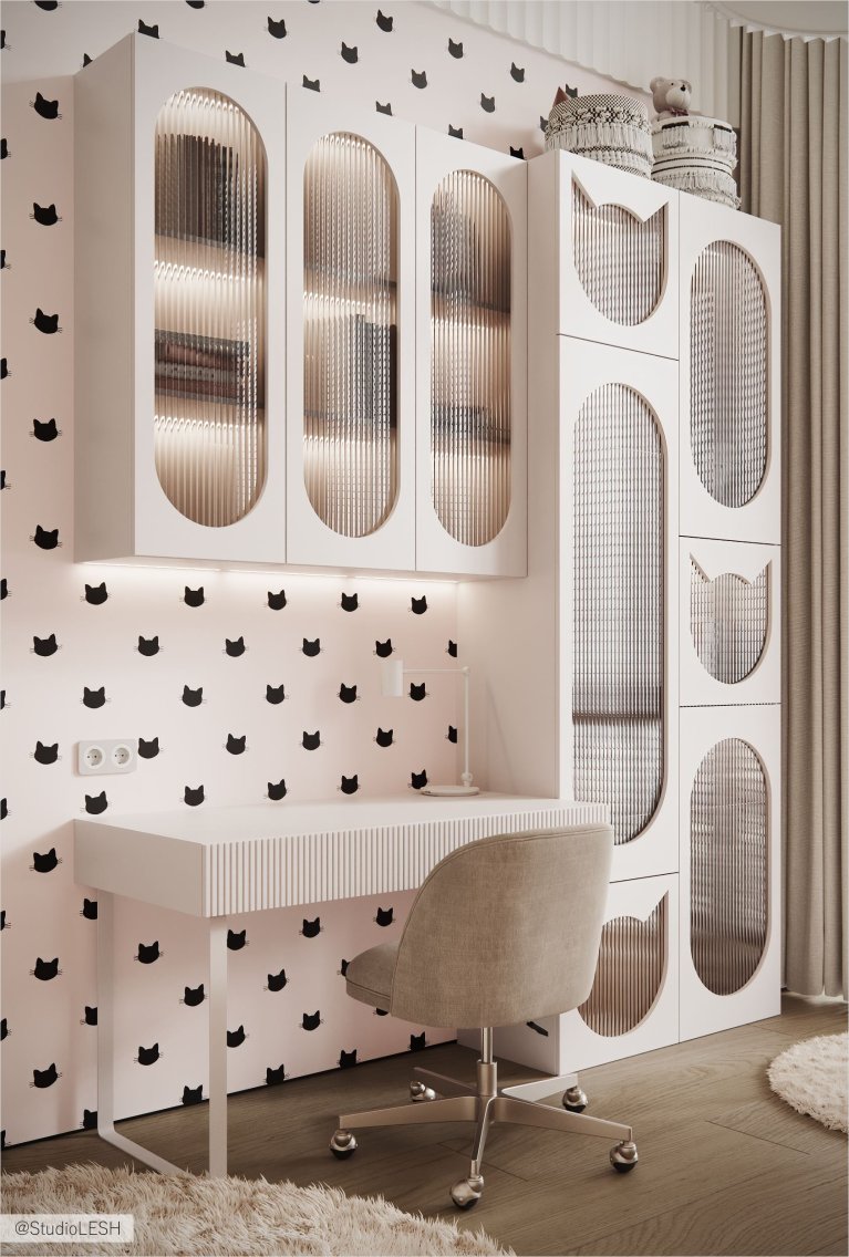 Интерьер современной детской комнаты с белым столом, стулом, шкафом с открытыми полками и стеклянными дверцами, а также обоями с рисунком в виде кошек.