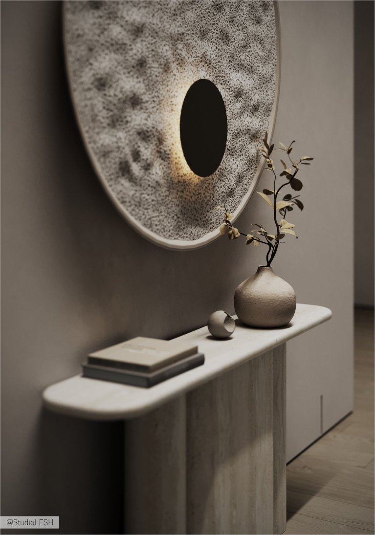 На белой консоли с круглой столешницей стоят две книги, керамическая ваза с веткой и круглое зеркало с подсветкой.