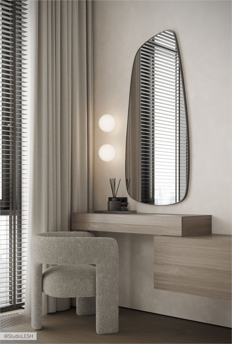 Интерьер современной комнаты с деревянным туалетным столиком, зеркалом необычной формы, мягким стулом и окном с жалюзи.