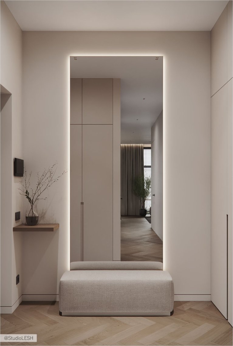 Стильный коридор с большим зеркалом, визуально увеличивающим пространство. Перед зеркалом стоит удобная скамейка, а рядом - столик с вазой и минималистичной вешалкой. Встроенные шкафы обеспечивают достаточно места для хранения