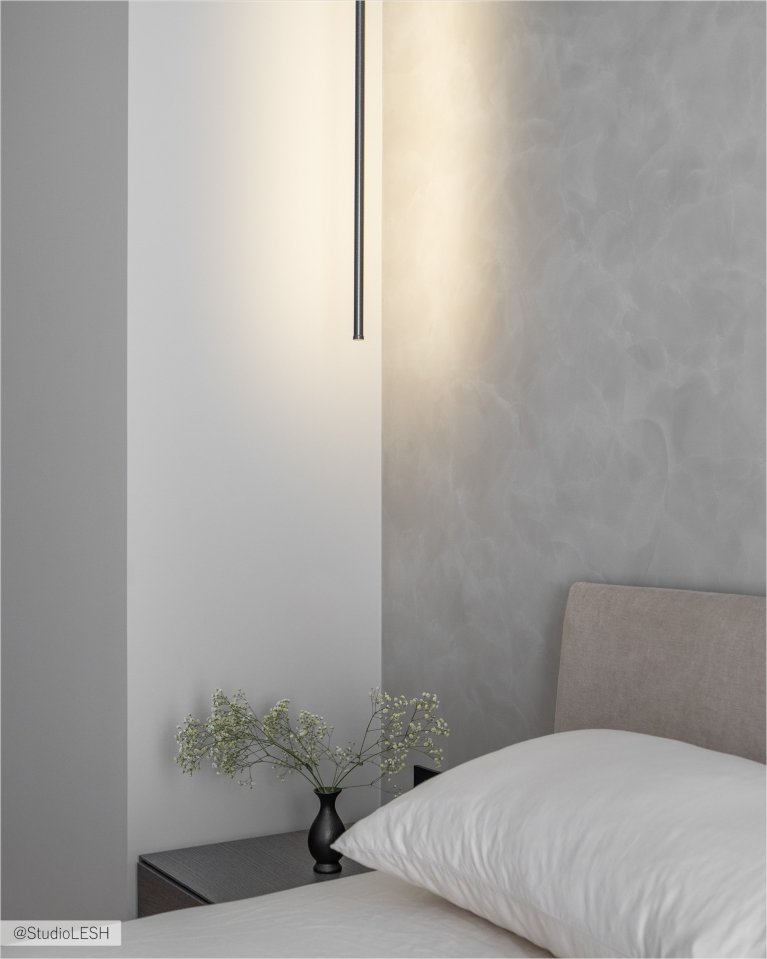 Уютная спальня с большой кроватью, застеленной серым покрывалом, и декоративными подушками. На стене за кроватью - деревянная панель, а по бокам - две тумбочки с лампами. В комнате также есть большое окно с жалюзи и плотными шторами, пропускающими мягкий свет