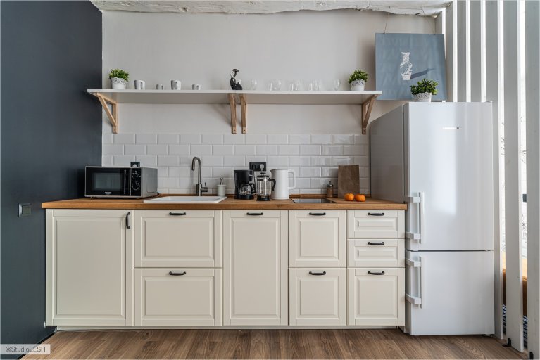 Светлая и просторная кухня с белыми фасадами, деревянными столешницами и современными бытовыми приборами
