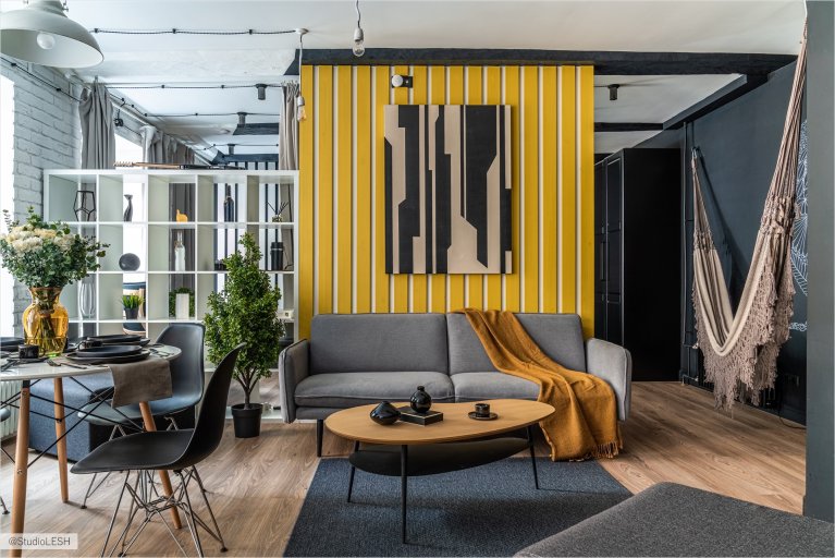 Светлая гостиная с паркетным полом, удобным диваном и жёлтой стеной, создающей атмосферу тепла