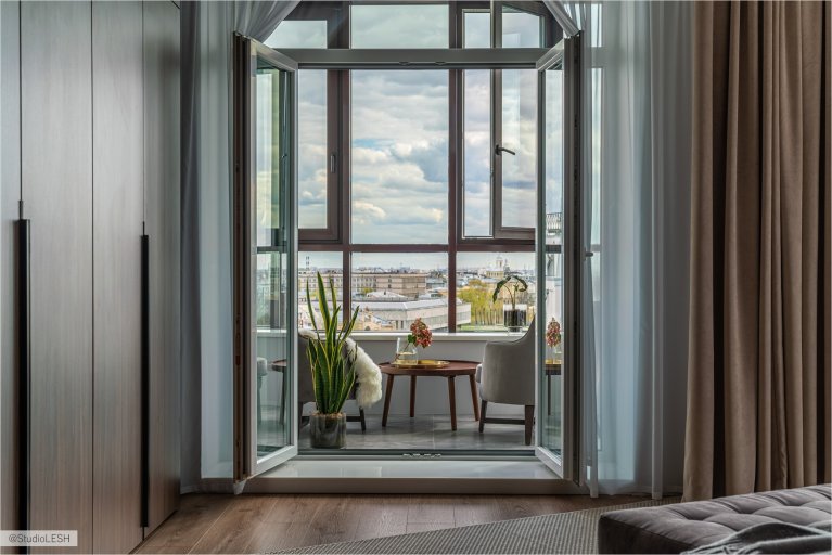 Современная лоджия с панорамным видом на город, стильной мебелью и растениями