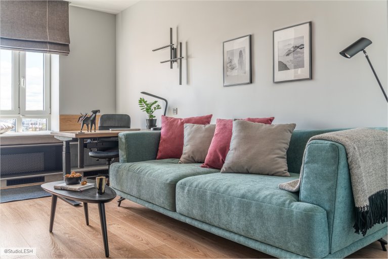 Современная гостиная с диваном, рабочим местом у окна и стильными элементами декора