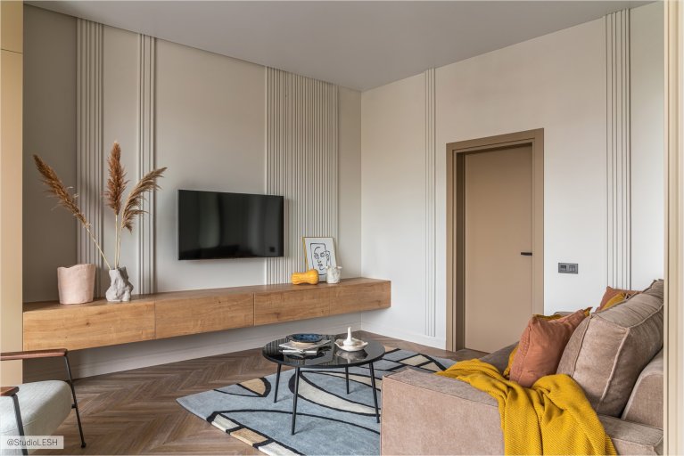Современный дизайн гостиной с подвесной тумбой под телевизор, декоративной панелью на стене и стильным диваном