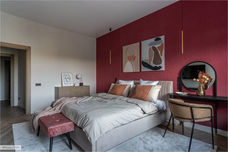 Спальня с большой кроватью с мягким изголовьем, на которой лежат декоративные подушки и покрывало